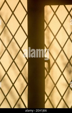 Sun shining through a leaded window forming a silhouette on a fabric blind in a cottage. Stock Photo