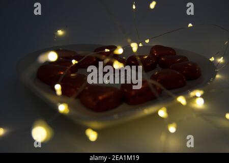 Chocolate hearts on a heart shaped plate with fairy lights Stock Photo