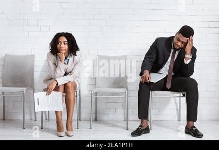 African American man and woman feeling exhausted from waiting for job interview at office hall, panorama Stock Photo