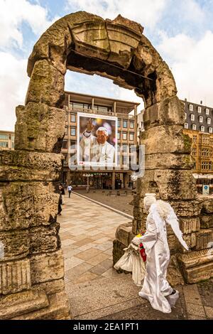 Actor disguised as an angel at Cologne Cathedral in front of Pope Benedict's poster, Germany Stock Photo