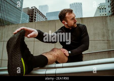 Handsome caucasian male athlete stretching legs running in city exercising for fitness training Stock Photo