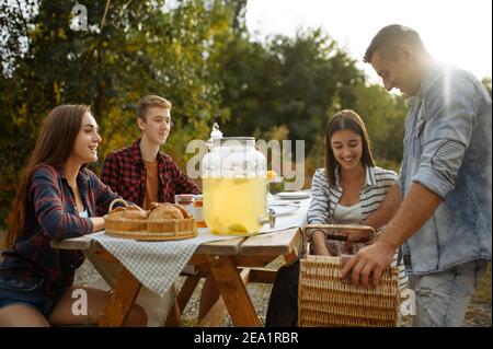 Friends sitting at the table on picnic at camping Stock Photo