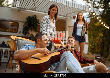 Friends sing songs with guitar, picnic at camping Stock Photo