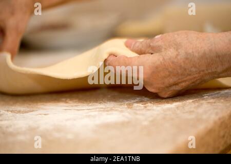 hands of an old woman roll out the dough close-up macro Stock Photo