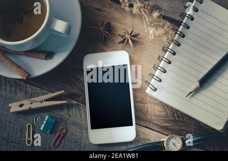 tea cup with books eyeglass notebook smart phone and pencil on the wooden table - tone vintage Stock Photo