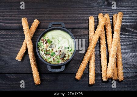 Avocado dip (hummus) with nibbles arranged on brown wooden background, text free space Stock Photo