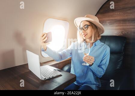 Asian businesswoman flies in business class on a corporate plane and works with a laptop and smartphone. Concept of a successful startup and transport Stock Photo