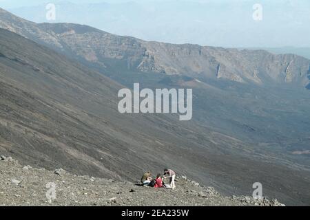ETNA NATIONAL PARK, SICILY, ITALY - OCTOBER 18, 2014: tourists on the edge of the ash steep slopes of Bove Valley; in the background, under the rocky Stock Photo
