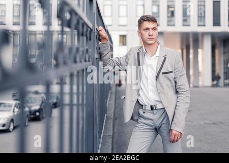 a budding young man in formal clothes poses on the porch of an office building in the city Stock Photo
