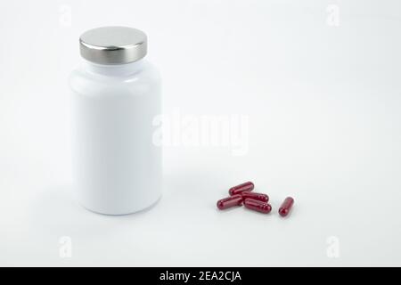 Pills bottle with red pills isolated on white background. Stock Photo