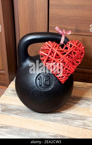 On a wooden background, a black weight with a heart as a gift for Valentine's Day. Stock Photo