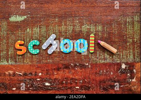 Auburn wooden table with colorful letters that make up the word school. Stock Photo