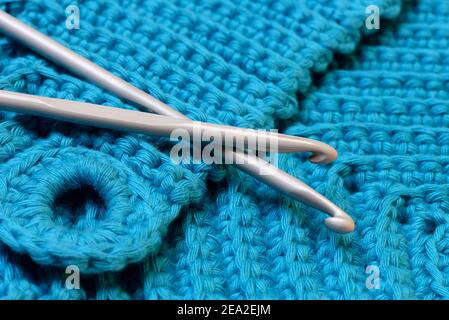 knitting pink crochet hooks and woolen thread on a blue background