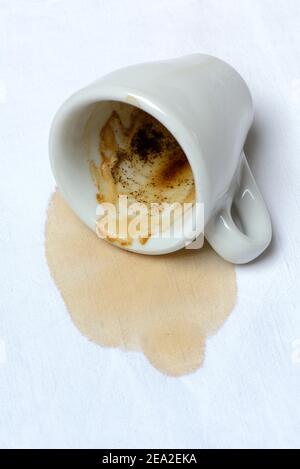 Coffee stain on tablecloth and fallen cup, spilled Stock Photo