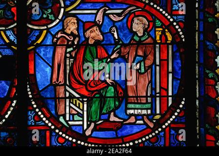 Saint Étienne or Saint Stephen (right) is made a deacon of the early Christian Church at Jerusalem by two Apostles in this vivid roundel of early 1200s AD stained glass, one of a series depicting the saint’s life and martyrdom, in the southern lancet window in the east choir wall of the medieval Gothic Cathédrale Notre-Dame de Laon at Laon, Aisne, Hauts-de-France, France. Stock Photo