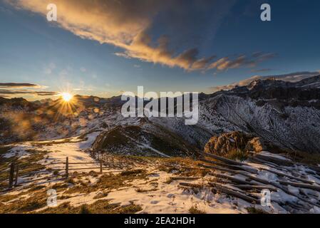 Morning sun rises over the peaks of the Fanes-Sennes-Braies mountains and on the snow-covered Kreuzkofeljoch, Puez-Odle range, Dolomites, South Tyrol Stock Photo