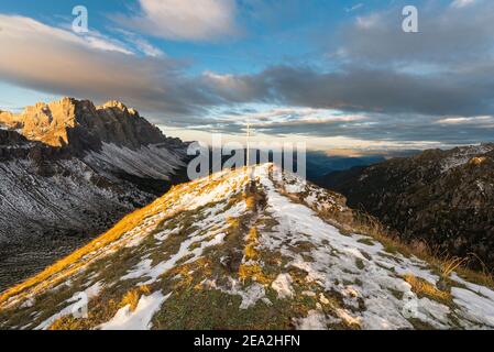 Summit cross of the Zendleser Kofel and view of Puez-Odle mountains in the Dolomites in autumn in the morning sun,  South Tyrol, Italy
