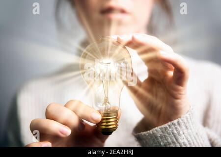 Female hand holding a shining light bulb, Great idea, innovation and inspiration, business concept background Stock Photo