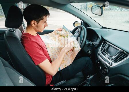 young man reads the map and looks for the destination driving his car. Travel and trip concept Stock Photo