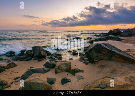 sea landscape at dawn. rocks on the sandy beach. clouds on the sky. summer vacation concept Stock Photo