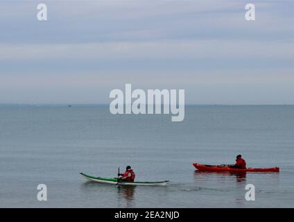Two kayakers embark on a trip from Knoll Beach, Studland, Dorset across Weymouth Bay. Stock Photo
