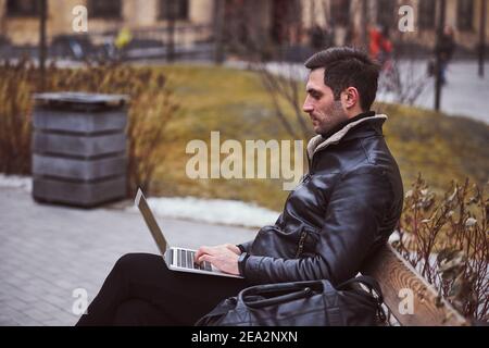 Young man using laptop in urban street Stock Photo