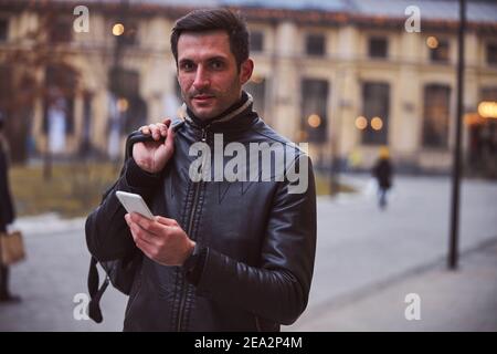 Smiling young man using cell phone outdoors Stock Photo