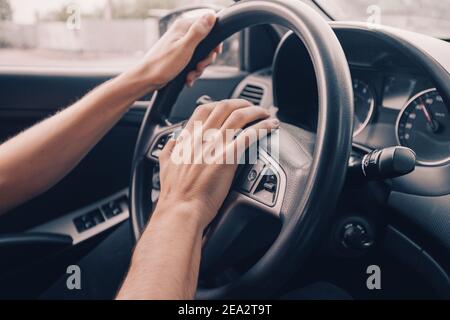 angry driver presses the horn of the car to attract the attention of the car bully and avoid road accident. Stress and aggressive driving on city stre Stock Photo