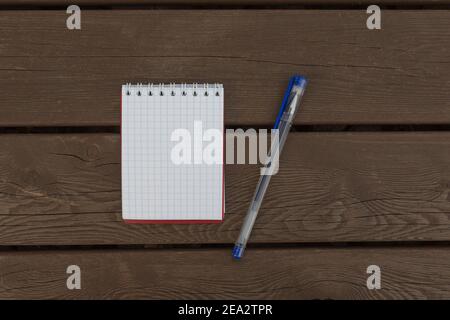 checkered notebook with ballpoint pen on brown wooden background Stock Photo