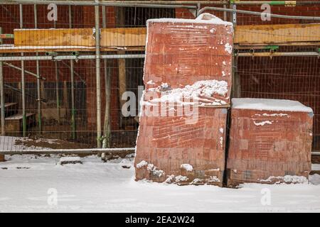 Pile of red building construction bricks under winter snow in england uk Stock Photo