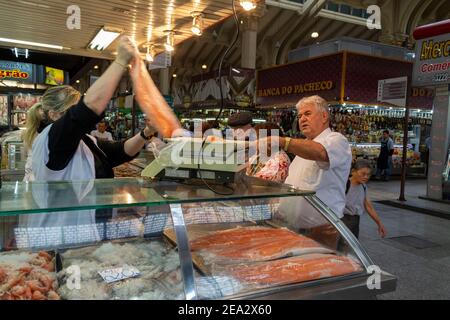 A customer purchases a large salmon at the historic public under covered Municipal Market (Mercado Municipal de Sao Paulo) on Rua da Cantareira in Sao Stock Photo