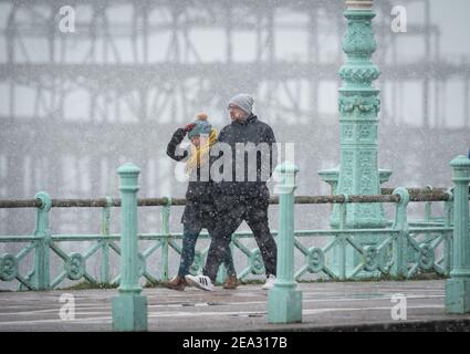 Two people walk along the seafront near West Pier in Brighton, Sunday Feb 9, 2021 Stock Photo