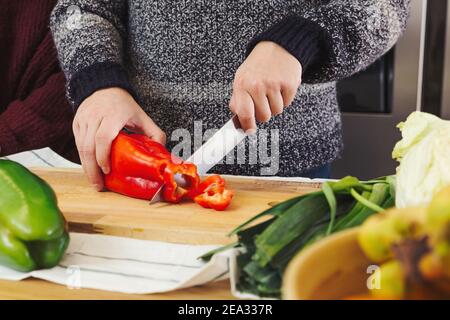 Stock photo of a close up shot of a man's hands cutting vegetables in the kitchen, preparing a vegan food and healthy meal Stock Photo
