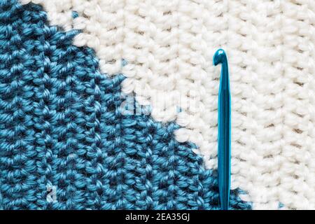 Handmade close-up simple blue and white crochet pattern with crochet hook Stock Photo
