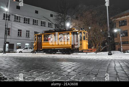 Old tram on the streets of medieval town with stone pavement at night. The Last Tram of Vyborg, Russia.  Stock Photo