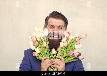 Spring mood. happy birthday concept. stay romantic at any season. man presenting flowers. mothers day. Waiting for his girlfriend. man in jacket holding bouquet of flowers. tulips for womens day. Stock Photo