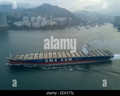 Aerial view from a drone of a container ship, carrying bulk containers through one of Asia's busiest shipping lanes - the Lamma Channel - between Aberdeen on Hong Kong island and Lamma island. The route is so busy that each vessel requires a pilot boat to and from the docks in order to navigate this part of the sea. © Olli Geibel Stock Photo