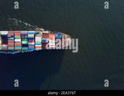 Aerial view from a drone of a container ship, carrying bulk containers through one of Asia's busiest shipping lanes - the Lamma Channel - between Aberdeen on Hong Kong island and Lamma island. The route is so busy that each vessel requires a pilot boat to and from the docks in order to navigate this part of the sea. © Olli Geibel
