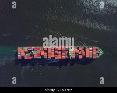 Aerial view from a drone of a container ship, carrying bulk containers through one of Asia's busiest shipping lanes - the Lamma Channel - between Aberdeen on Hong Kong island and Lamma island. The route is so busy that each vessel requires a pilot boat to and from the docks in order to navigate this part of the sea. © Olli Geibel Stock Photo