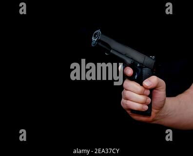 Hand holding a gun, isolated on black background. Stock Photo