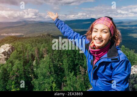 Happy Asian hiker woman enjoys climbing on high mountain in national Park. Beautiful view of the valley Stock Photo