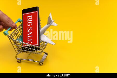 Shopping cart with plane toy. Air tickets sale concept. Stock Photo