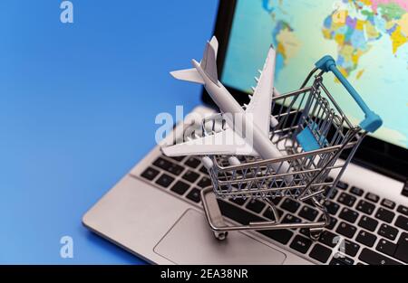 Shopping cart with plane toy. Air tickets sale concept. Stock Photo