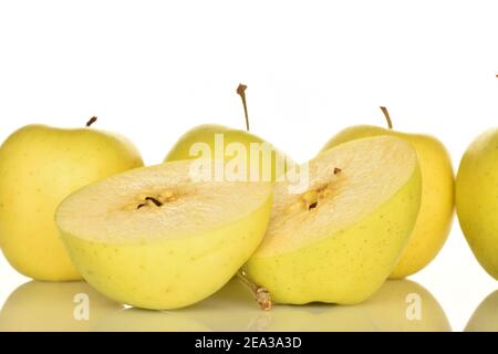 In the foreground, in focus, two halves of a yellow ripe tasty sweet aromatic apple on a white background. In the background, four whole apples. Stock Photo