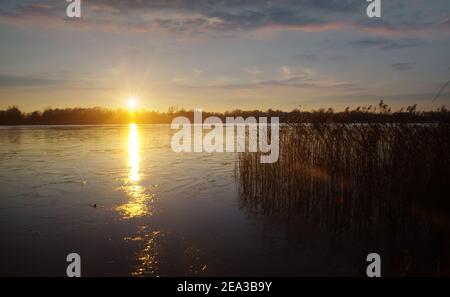 Winter sunset with reflection of sunlight on ice on the frozen lake Stock Photo