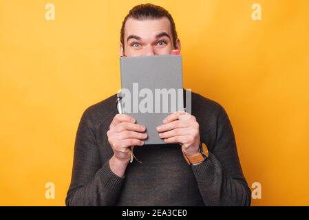 Portrait of man holding agenda or planner over face. Stock Photo