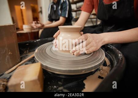 Close up of unrecognizable young woman shaping clay on pottery wheel in workshop while enjoying arts and crafts, copy space Stock Photo