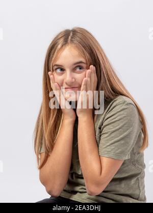 Young smiling girl looks to the side with sly and surprised expression Stock Photo