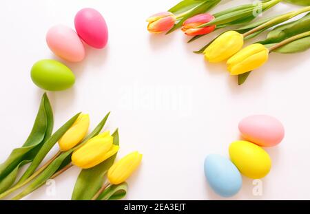 Beautiful yellow tulips and Easter eggs on a white background, top view. Stock Photo