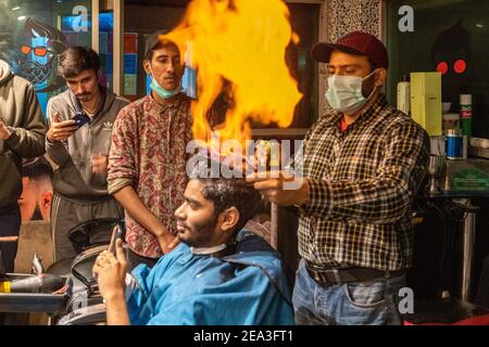 In Lahore, a hairdresser has developed a unique technique to cut gentlemen's hair: he sets the hair ablaze Stock Photo